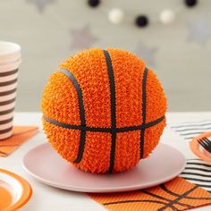 a cake shaped like a basketball sitting on top of a plate next to a cup