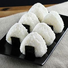 four pieces of sushi on a black plate