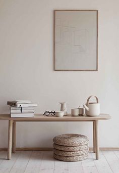 a table with books and cups on it in front of a framed art piece above