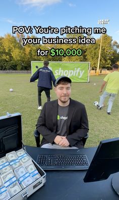 a man sitting in front of a laptop computer on top of a table with stacks of money