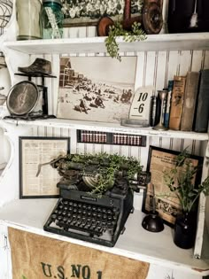 an old fashioned typewriter sitting on top of a white shelf filled with books and other items