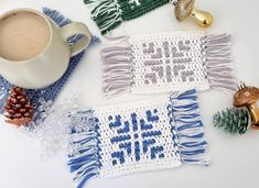 three crocheted coasters with blue and white designs on them next to a cup of coffee