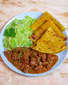 a white plate topped with meat and veggies next to tortilla bread