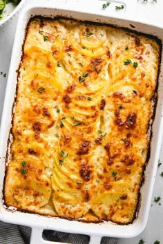 a casserole dish with cheese, onions and parsley in it on a table