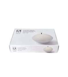 two white candles sitting on top of a box