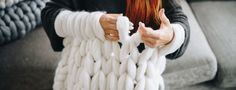 a woman holding a large white rope on top of a gray couch next to a pillow