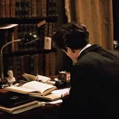 a man sitting at a desk in front of a book shelf with books on it