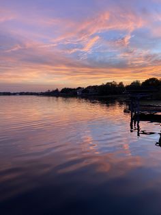 the sky is reflected in the calm water at sunset, with boats on the dock