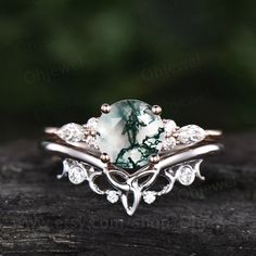 a green and white ring sitting on top of a piece of wood with diamonds around it