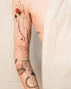 a man's arm with flowers and butterflies on it, next to a white wall