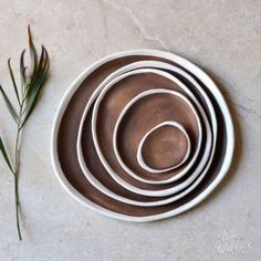 four brown and white bowls sitting on top of a table next to a green plant