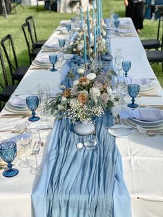 the table is set with blue and white dishes, silverware, and candlesticks