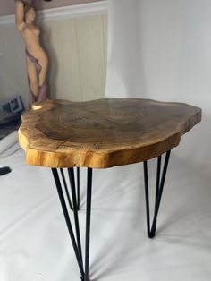 a wooden table with hairpin legs and a woman in the background on a white backdrop