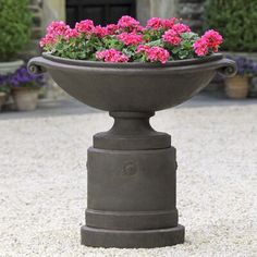 a planter filled with pink flowers sitting on top of gravel