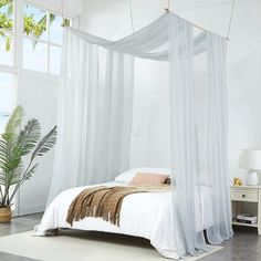 a white bed with sheer curtains over it