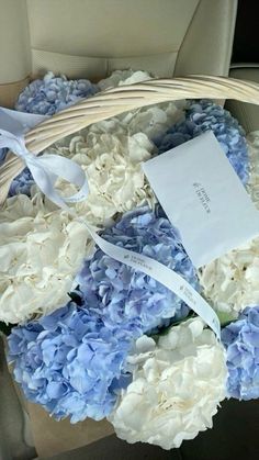 a basket filled with blue and white flowers on top of a car seat belt next to a note