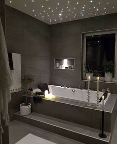 a bathroom with a large bathtub and lights on the ceiling, along with two candles