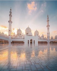 a large white building with many towers and domes on it's sides at sunset