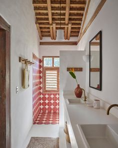 a bathroom with red and white tile on the floor, sink and shower curtain in the window