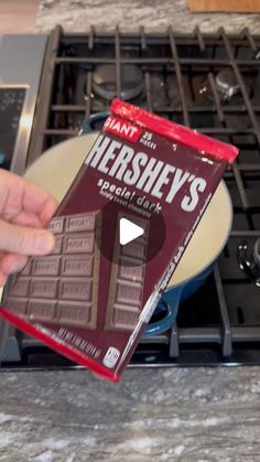 a person holding up a hershey's chocolate bar in front of an oven