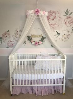 a white crib with pink flowers on the wall