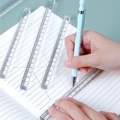 a person holding a pen and writing on a notebook with lined paper next to them