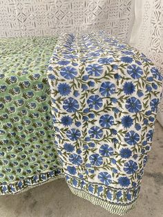 a blue and green table cloth on top of a white chair with floral print design