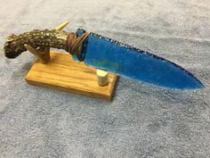 a blue knife with a wooden stand on a gray toweled surface next to it