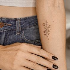 a woman's arm with a small flower tattoo on the left side of her body