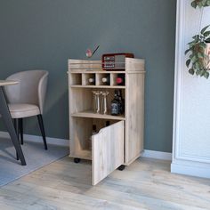 a small wooden cabinet with wine glasses and bottles in it, next to a chair