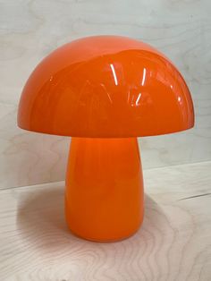 an orange mushroom lamp sitting on top of a wooden table