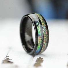 a black ring with an iridescent green and yellow inlay