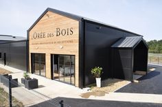 an empty building with black roofing and wooden walls on the side of the road