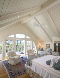 a bedroom with a large bed and two chairs next to each other on a wooden floor