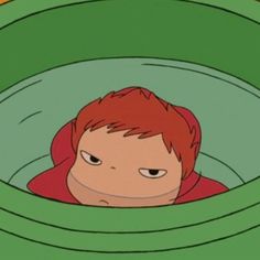 a boy with red hair is in a green round pool and looks at the camera