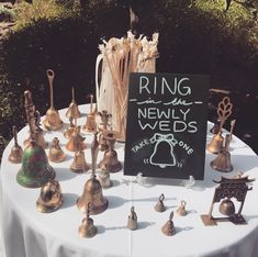 a table topped with lots of brass bells and a sign that says ring the newly weds