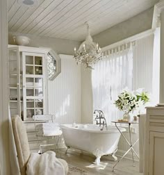 a white bath tub sitting inside of a bathroom next to a sink and toilet under a chandelier