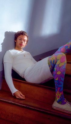 a man sitting on the stairs with his legs painted like flowers and wearing leggings