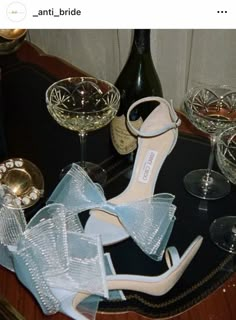 a pair of high heeled shoes sitting on top of a table next to wine glasses