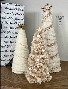 two small white christmas trees sitting on top of a wooden table next to each other