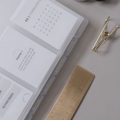 a pair of scissors next to some business cards and a gold ruler on a table