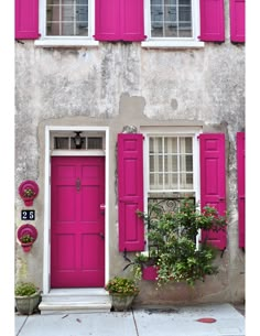 a pink house with red shutters and potted plants