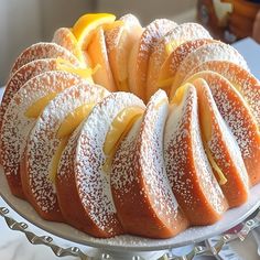 a cake with lemons and powdered sugar on top sits on a platter