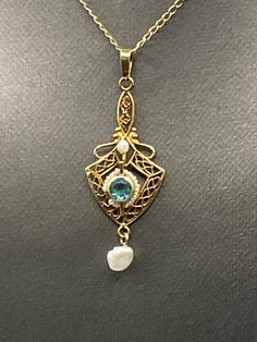 Ladies antique pendant is created in 10 karat solid yellow gold.  One round blue Obsidian stone is set in the middle of a halo of pearls, and a freshwater pearl suspends gracefully at the bottom.  The gorgeous filigree design work makes this pendant truly unique.   Weight:  1.0 grams Length:  1 ½"  Width:  ⅝" Our Price $299.00 Regularly Priced At $475.00 Please See Our Video Remember - If you're purchasing for yourself or a gift for a loved one, buy with confidence.  We Guarantee Everything We Sell!  SKU # P645 Exquisite Oval Pearl Drop Jewelry, Exquisite Pearl Drop Jewelry, 14k Gold Pearl Drop Pendant Jewelry, Antique Pearl Pendant Necklace For Formal Occasions, Exquisite Pearl Pendant Jewelry, Heirloom Style Yellow Gold Pearl Jewelry, Heirloom Yellow Gold Pearl Jewelry, Yellow Gold Pendant Jewelry With Pearl Drop, Yellow Gold Pearl Drop Pendant Jewelry