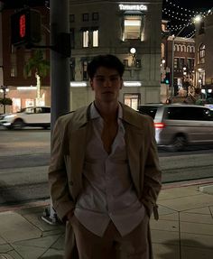 a man standing on the side of a street next to a traffic light at night