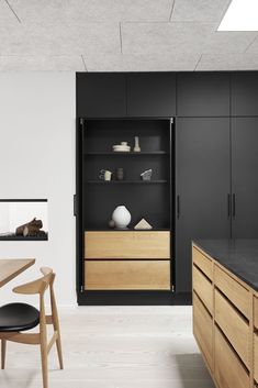 an open cabinet in the middle of a kitchen with black counter tops and wooden furniture