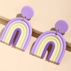 a pair of purple, yellow and white earrings with a rainbow design hanging from it