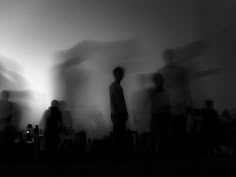 black and white photograph of people standing in front of a wall with blurry images