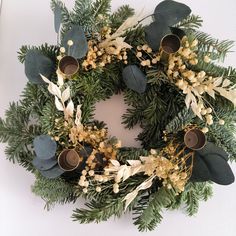 a wreath with candles and greenery is displayed on a white surface, ready to be used as an ornament