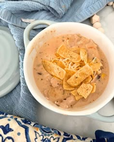 a bowl of soup with tortilla chips in it on a blue and white towel